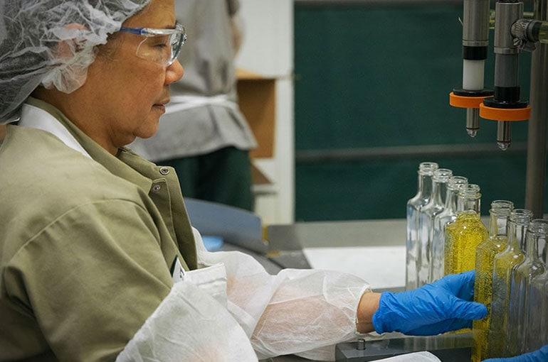 Woodland Gourmet employee carefully hand bottling oils for a customer.